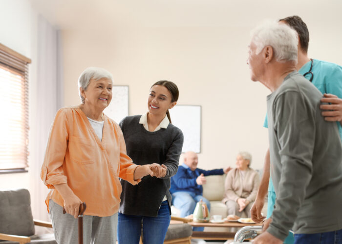 Une AES aide une personne âgée à se déplacer.