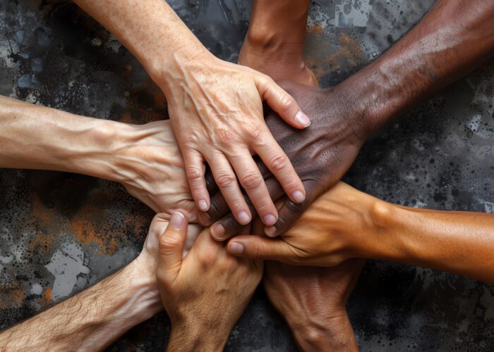 Des mains de toutes origines jointes, symbolisant l'unité, le travail d'équipe et la collaboration.